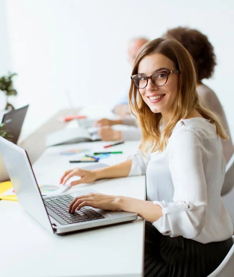 A woman sitting at a desk with a laptop, working diligently.