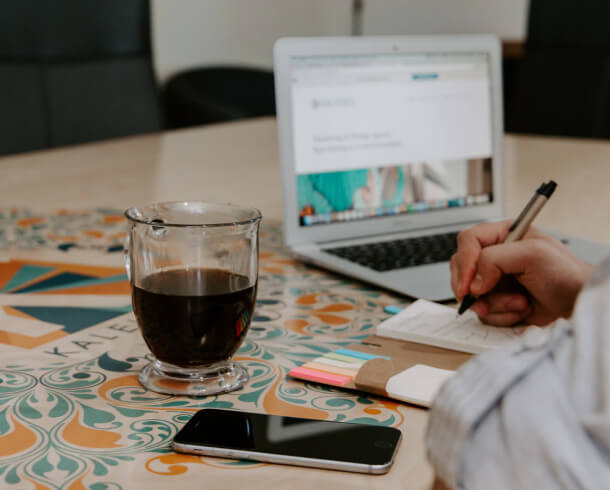 A person sitting at a table with a laptop and a glass of wine while working on technical tasks.
