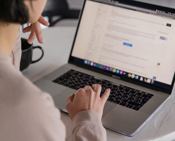 A woman is typing on a laptop at a table, engaging in Technical SEO Services.
