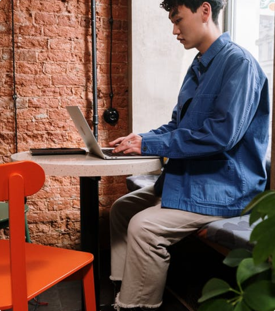 A man sitting at a table using a laptop to create an ebook.