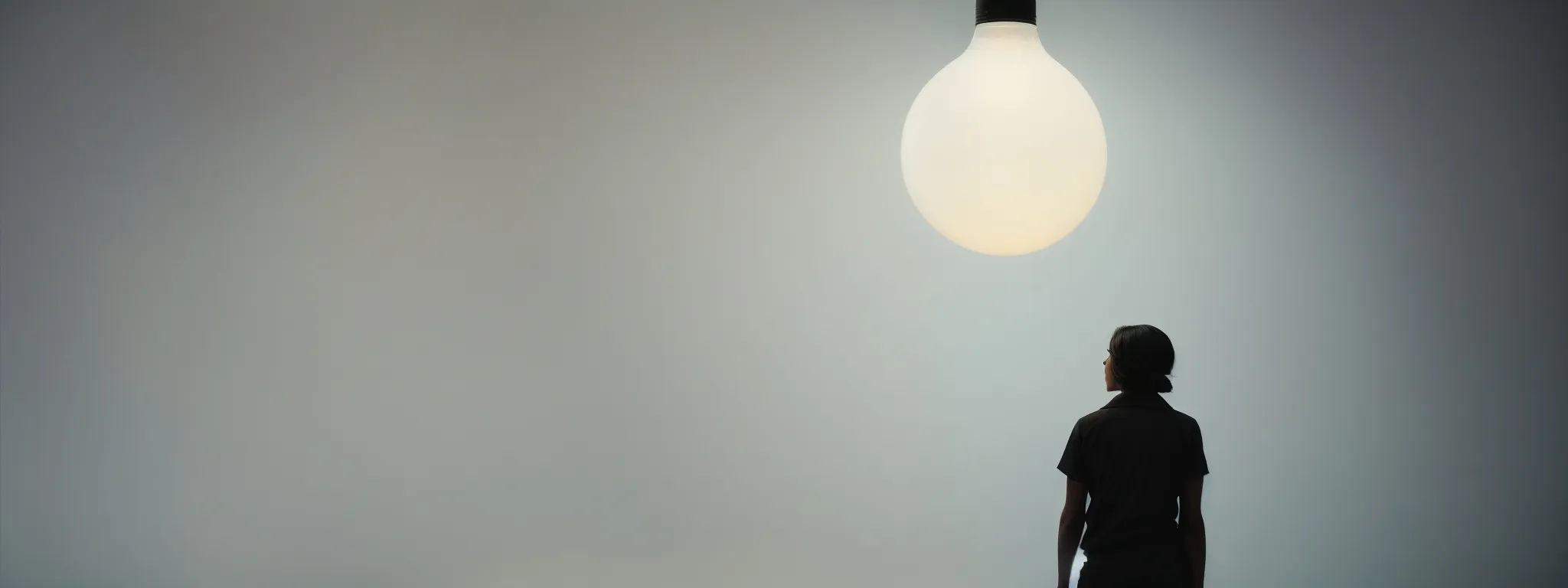 a person's silhouette stands before a giant light bulb, symbolizing a moment of creative inspiration within a digital interface.