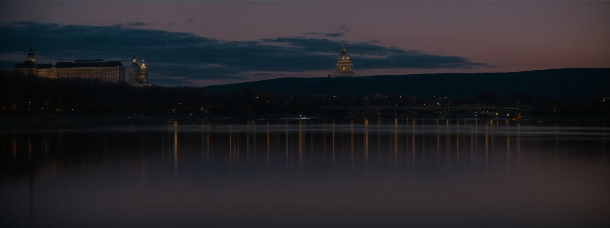 view of the harrisburg capitol building reflecting in the susquehanna river at dusk, symbolizing local presence.