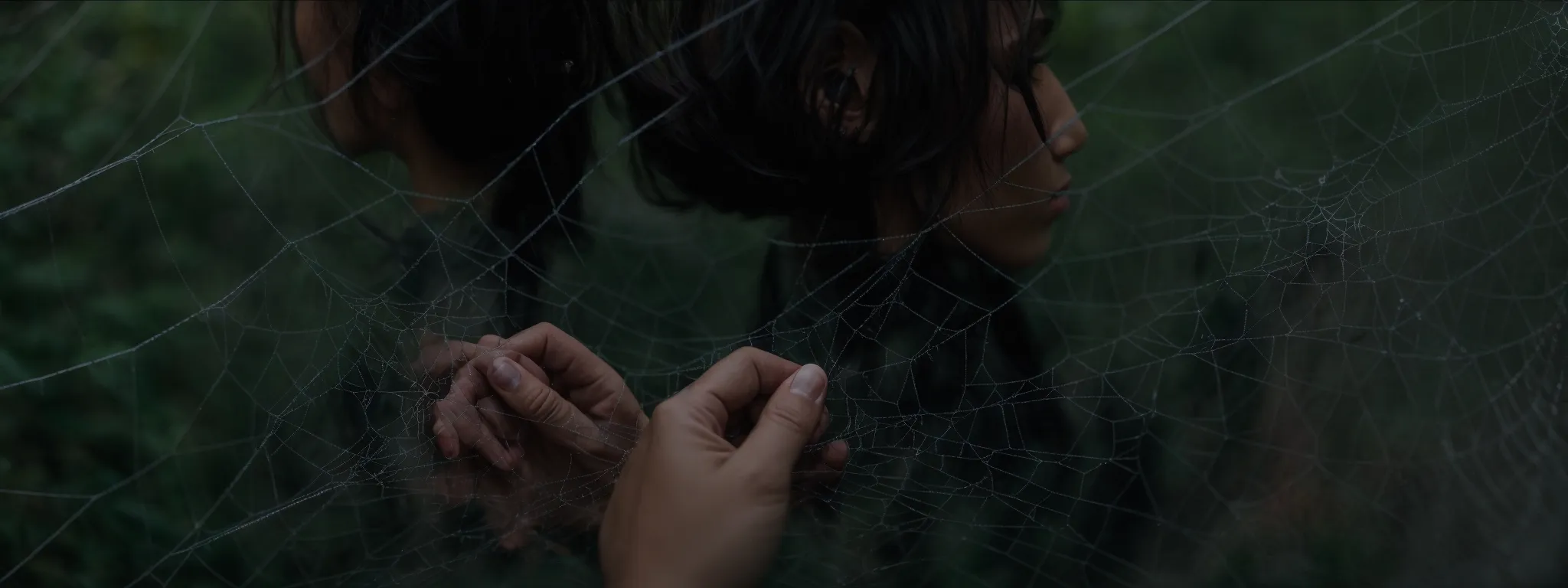 a person intently examining a large, tangled spider web, meticulously reconnecting severed strands.