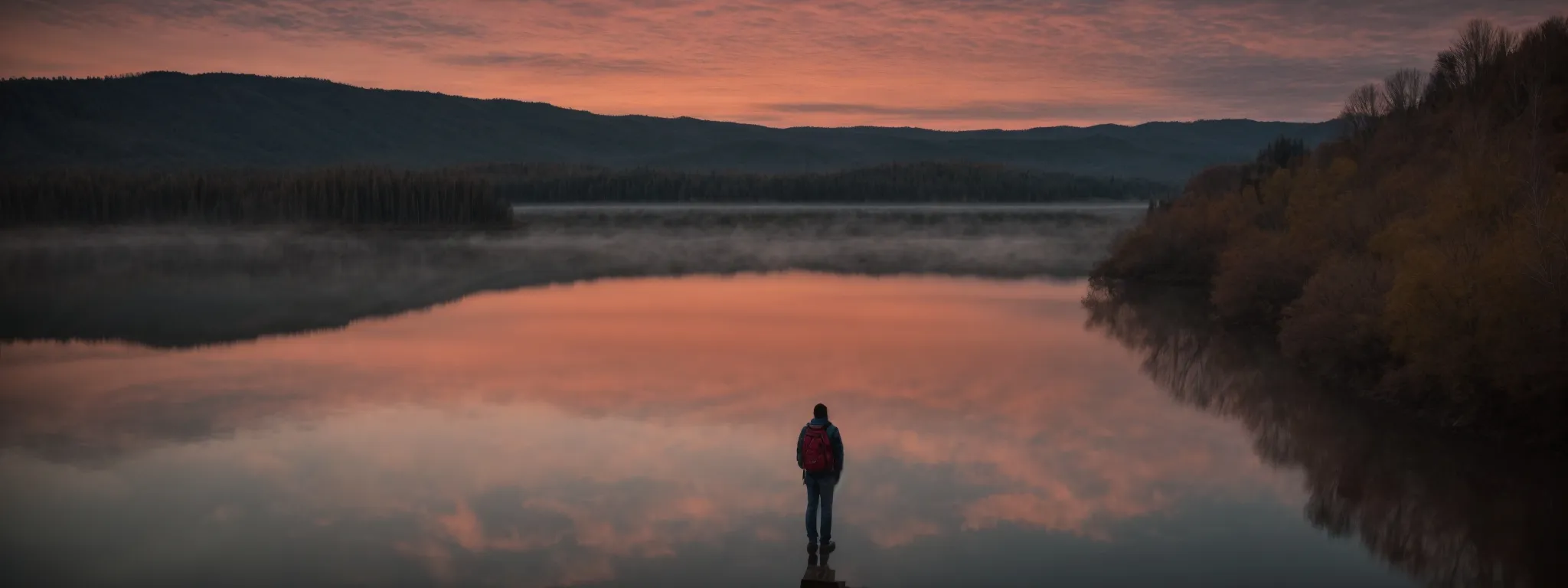 a person thoughtfully gazes at a vibrant sunrise over a calm lake, symbolizing new beginnings in the ever-evolving landscape of seo content marketing.