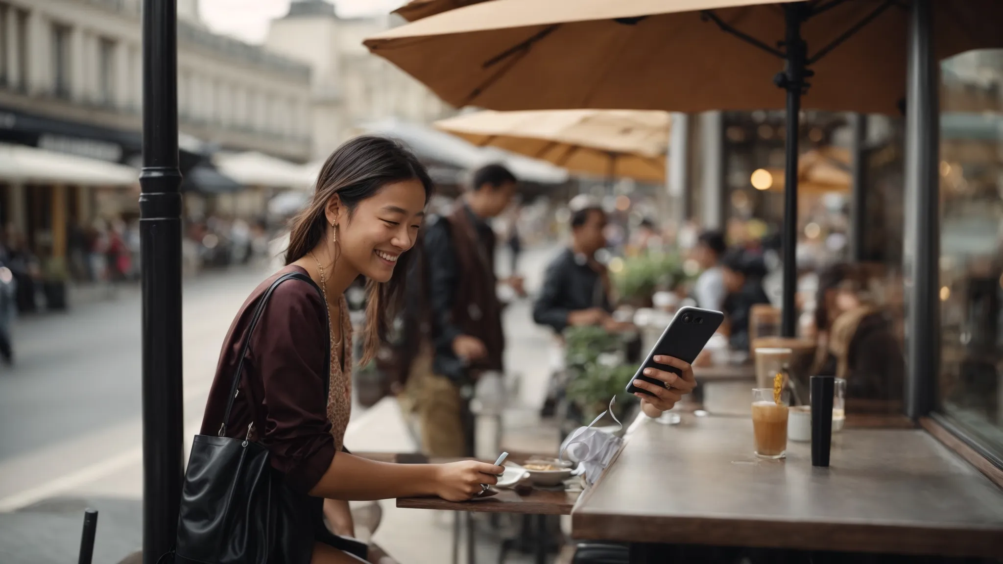 a customer smilingly using their phone outside a bustling cafe terrace.