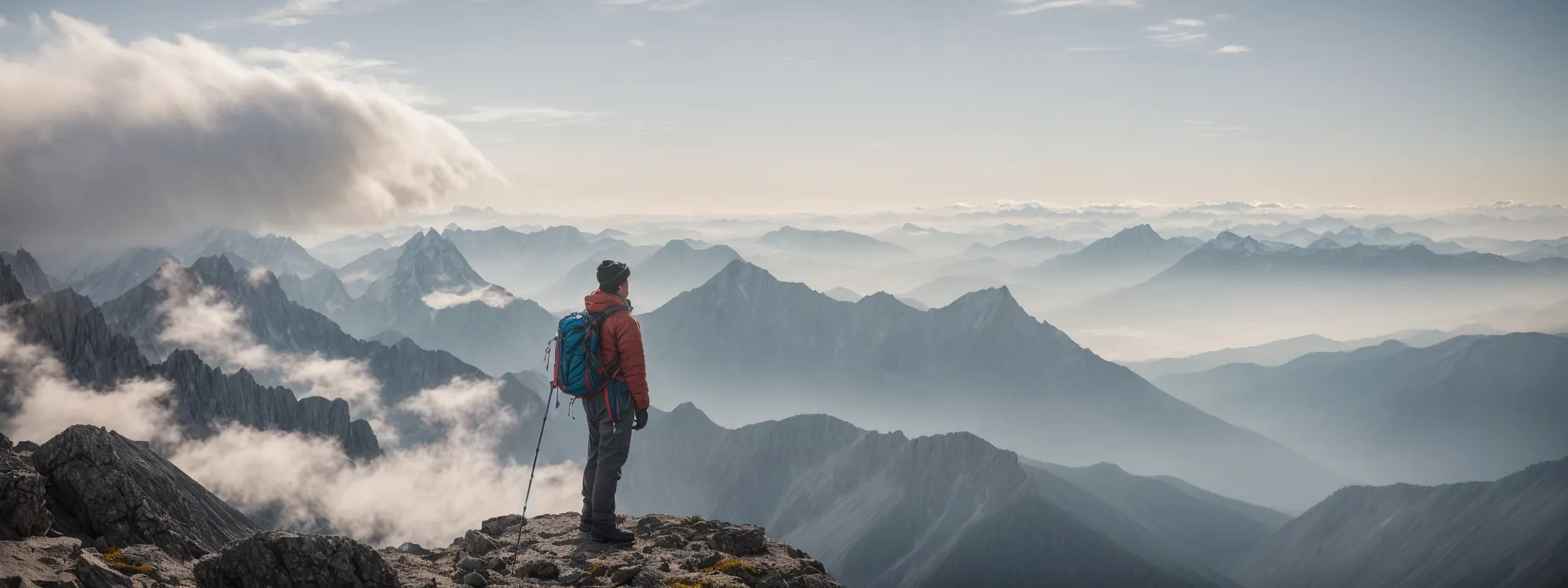 a mountaineer stands at a summit, gazing out over a panoramic vista of cloud-wreathed peaks, symbolizing the pinnacle of seo success achieved through linkgraph's software.