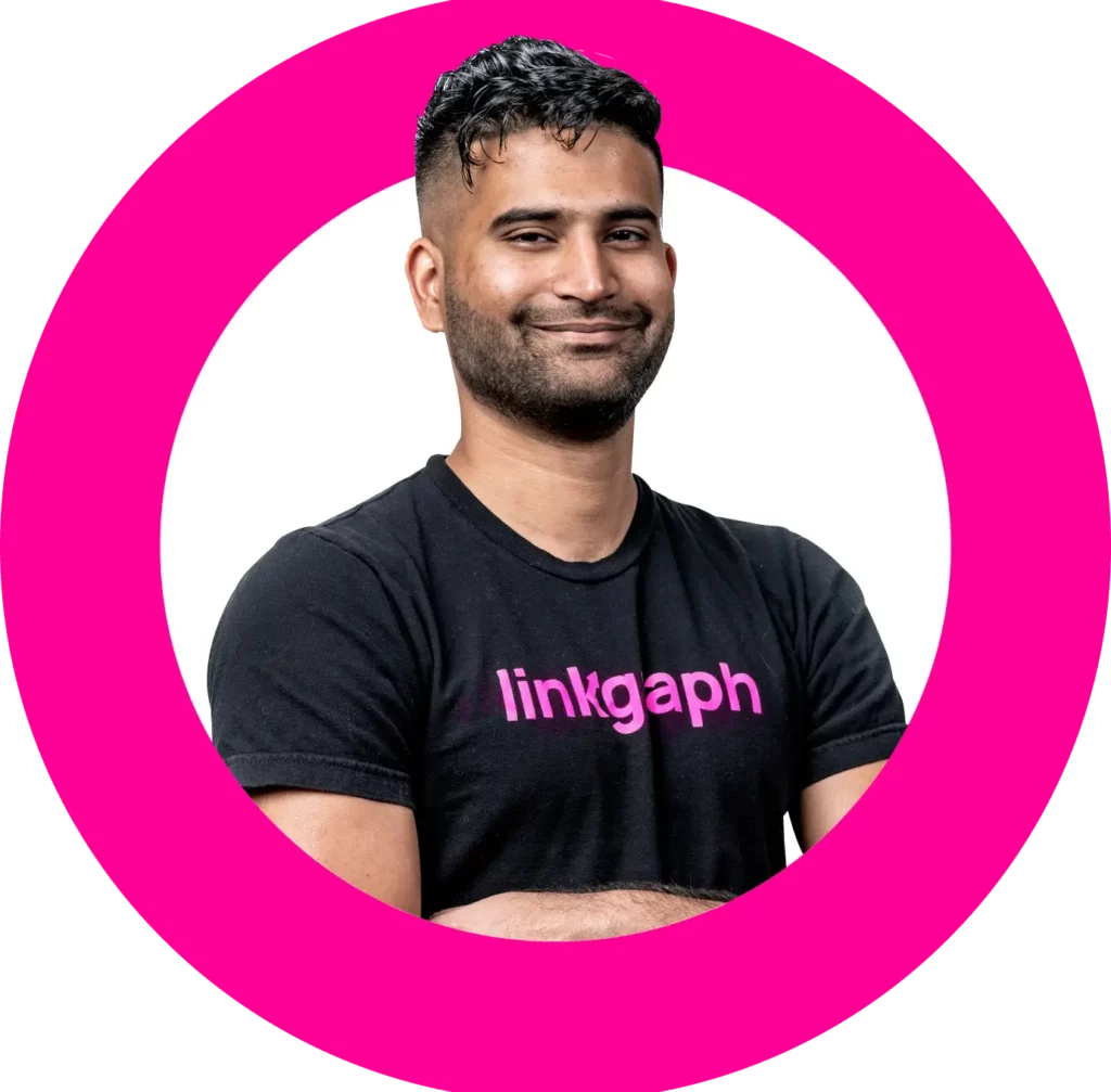 Person with short hair and beard, wearing a black "linkgaph" t-shirt, is smiling with arms crossed inside a pink circle.